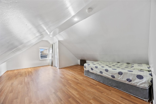 bedroom with lofted ceiling, wood finished floors, and baseboards