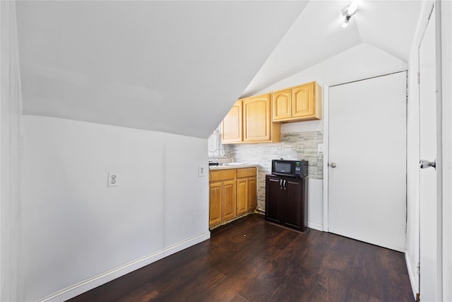 kitchen with tasteful backsplash, light brown cabinetry, dark wood-style floors, black microwave, and lofted ceiling