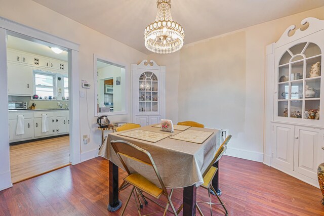 dining area featuring a toaster, an inviting chandelier, wood finished floors, and baseboards