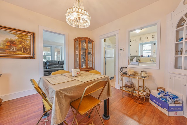 dining area with an inviting chandelier, wood finished floors, and baseboards