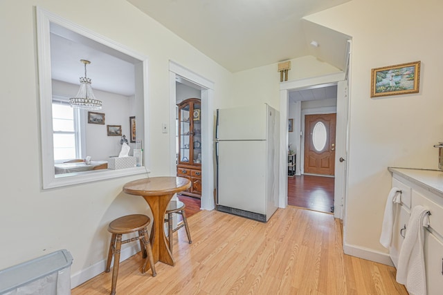 kitchen featuring light wood-type flooring, white cabinets, freestanding refrigerator, and baseboards