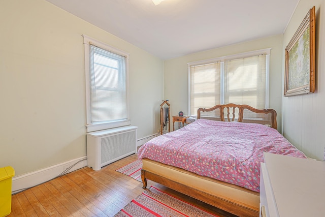 bedroom featuring baseboards, radiator, and light wood finished floors