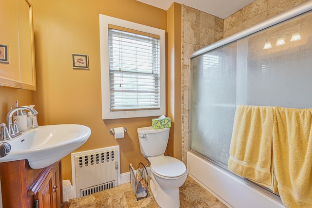 bathroom featuring tile patterned flooring, combined bath / shower with glass door, radiator heating unit, toilet, and vanity