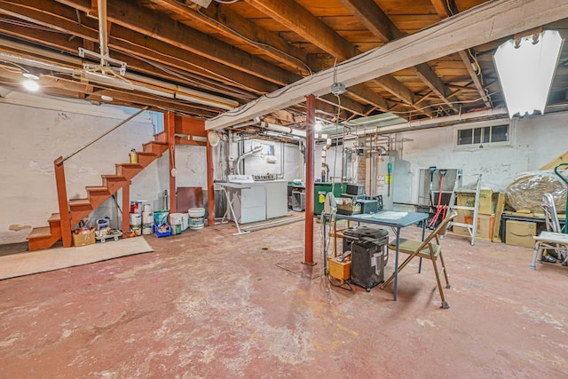 unfinished below grade area with gas water heater, stairs, and independent washer and dryer