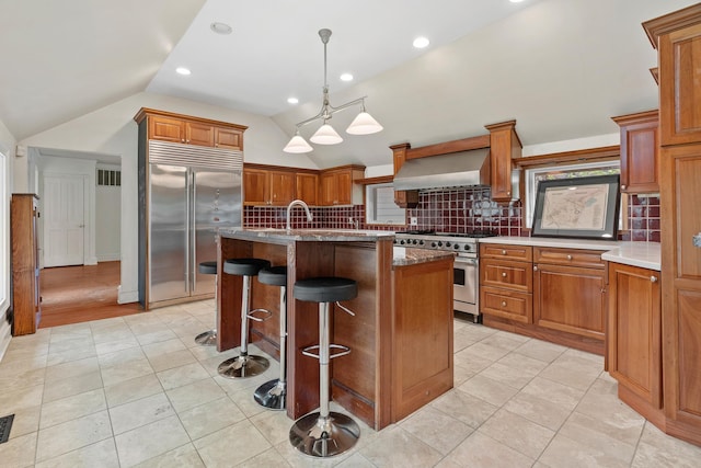 64 Paulding Ave, Cold Spring, NY 10516 - kitchen with wall chimney range hood, high end appliances, vaulted ceiling, and tasteful backsplash