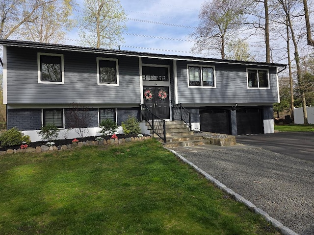 bi-level home with brick siding, a front yard, driveway, and an attached garage