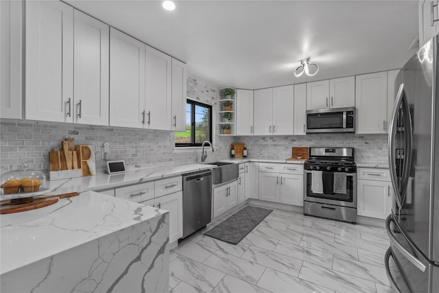 kitchen featuring decorative backsplash, open shelves, appliances with stainless steel finishes, white cabinets, and a sink
