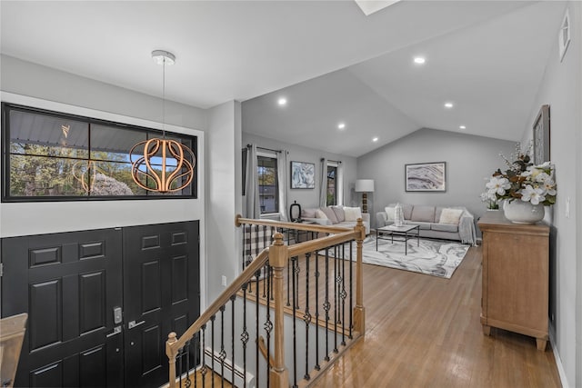 hall with wood finished floors, a healthy amount of sunlight, and an upstairs landing