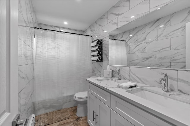 bathroom with double vanity, wood finished floors, toilet, and a sink