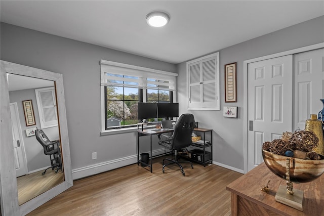 office space featuring light wood finished floors, baseboards, and a baseboard radiator