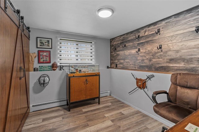 interior space featuring baseboard heating, a barn door, wood finished floors, and wood walls