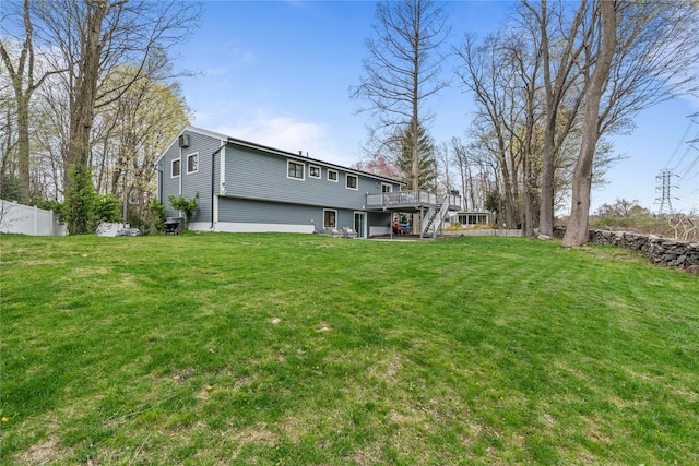 rear view of house featuring a lawn, fence, and a deck