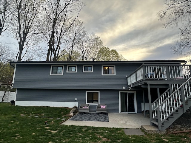 rear view of property featuring a lawn, a wooden deck, and a patio