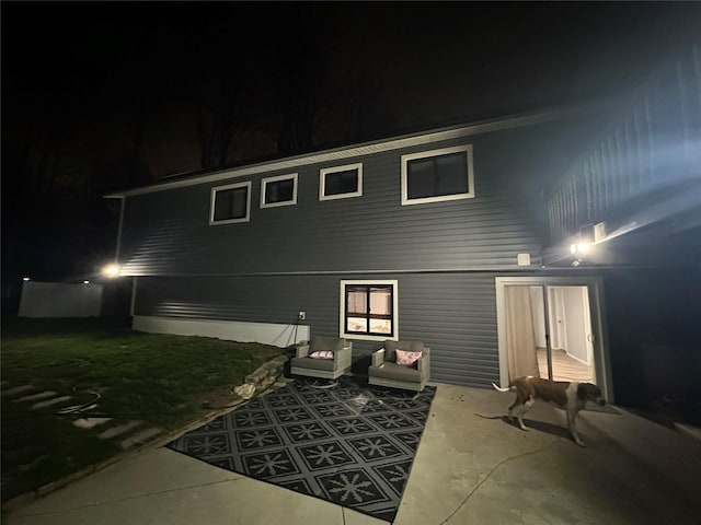 back of house at twilight featuring a patio