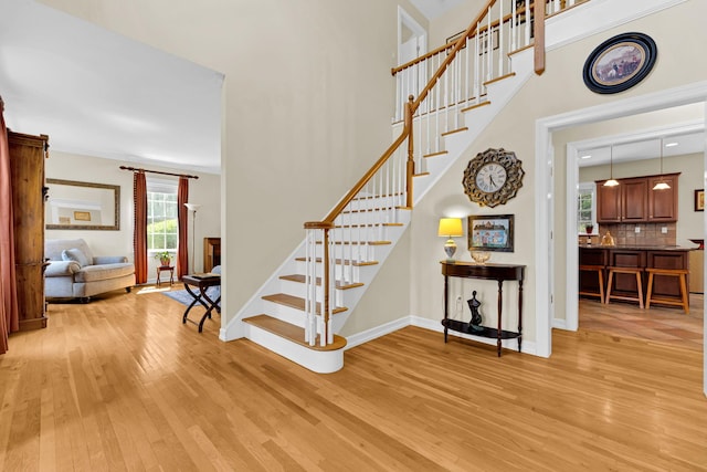 stairs with a towering ceiling, wood finished floors, and baseboards