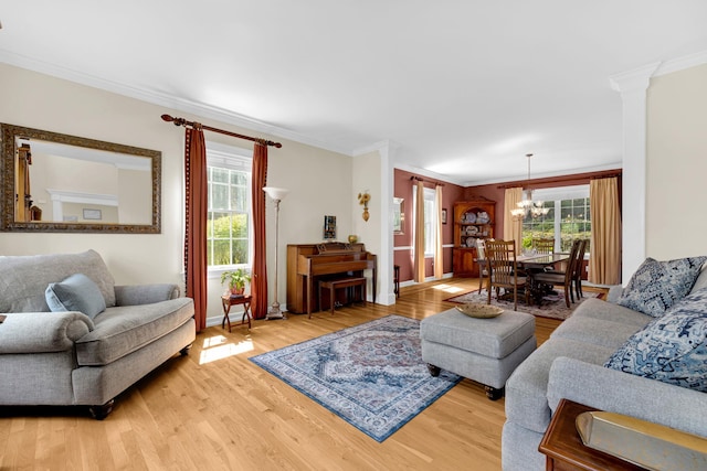 living room featuring a chandelier, baseboards, light wood-style floors, and crown molding