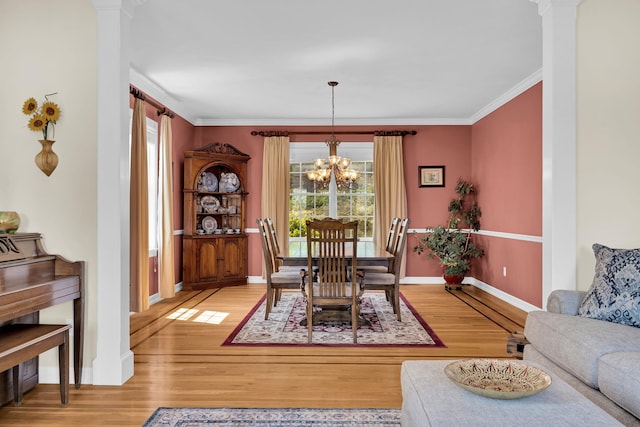 dining space with light wood-type flooring, crown molding, a notable chandelier, and baseboards