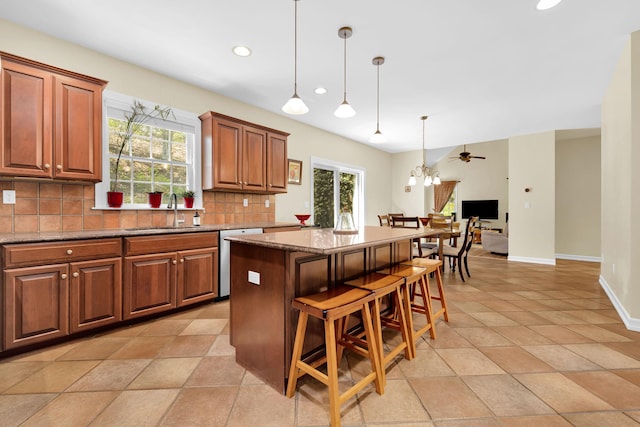 kitchen with a sink, decorative backsplash, a center island, dishwasher, and plenty of natural light