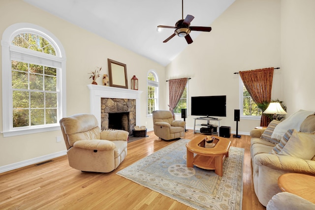 living room with visible vents, ceiling fan, a stone fireplace, and plenty of natural light