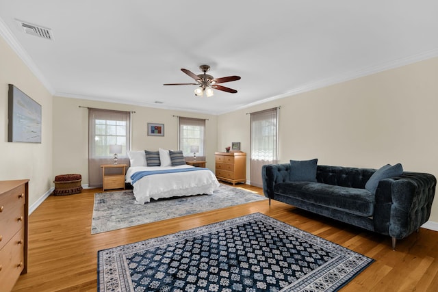 bedroom with ceiling fan, crown molding, visible vents, light wood-style flooring, and baseboards