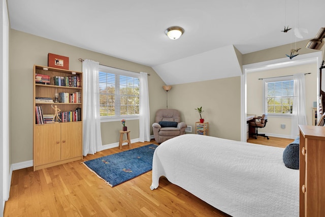bedroom featuring baseboards, multiple windows, and light wood finished floors