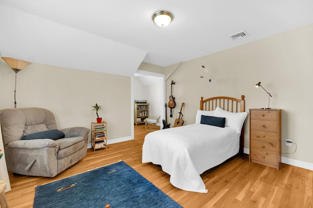 bedroom featuring lofted ceiling, visible vents, light wood-style flooring, and baseboards