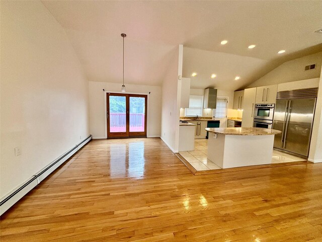 5 Elm St, Great Neck, NY 11021 - kitchen with visible vents, appliances with stainless steel finishes, vaulted ceiling, a baseboard heating unit, and light wood finished floors