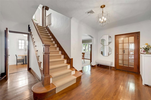 10 Maple Hill Dr, Larchmont, NY 10538 - foyer entrance featuring arched walkways, stairs, wood finished floors, a chandelier, and crown molding