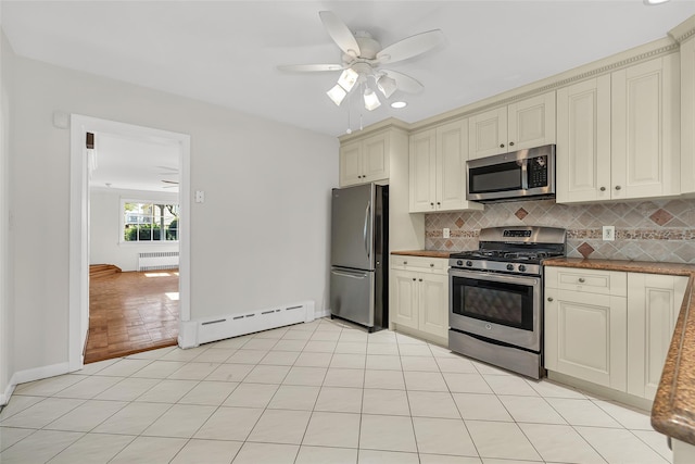 kitchen featuring decorative backsplash, appliances with stainless steel finishes, a baseboard radiator, cream cabinetry, and radiator heating unit