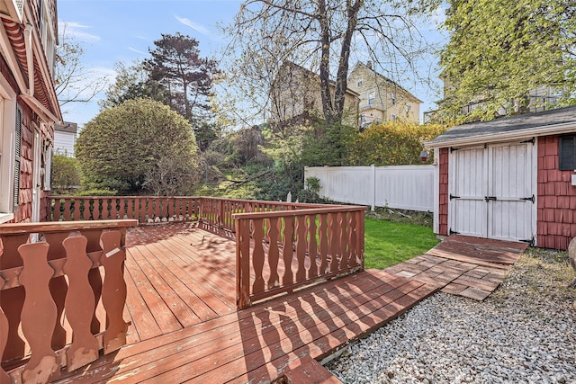 wooden deck with an outbuilding, a shed, and fence