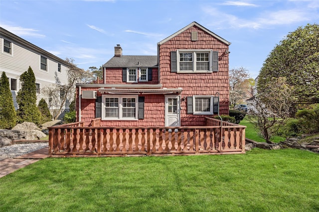 view of front of home with a wooden deck, a chimney, roof with shingles, an AC wall unit, and a front lawn