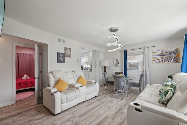 living room with cooling unit, visible vents, and light wood-style flooring