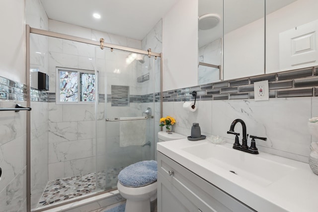 bathroom featuring tile walls, a shower stall, toilet, and vanity