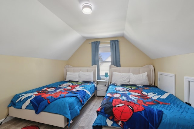 bedroom with wood finished floors and vaulted ceiling