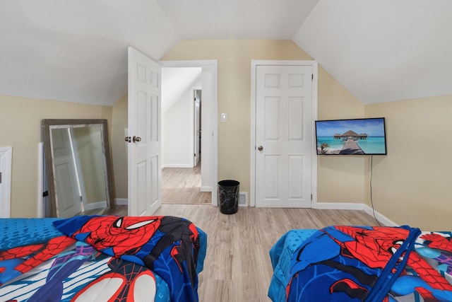 bedroom featuring baseboards, wood finished floors, and lofted ceiling