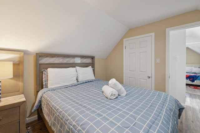 bedroom with lofted ceiling, wood finished floors, and baseboards