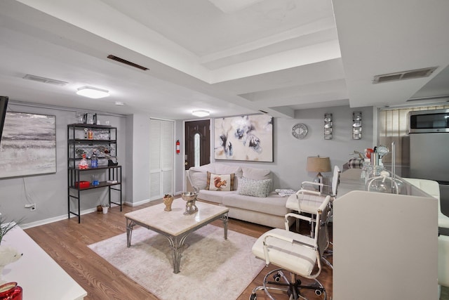 living room with visible vents, wood finished floors, and baseboards