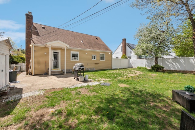 back of house featuring a patio, a lawn, a fenced backyard, and roof with shingles