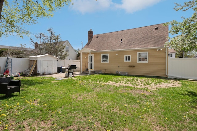 back of house with a patio area, an outbuilding, a fenced backyard, a storage shed, and a chimney