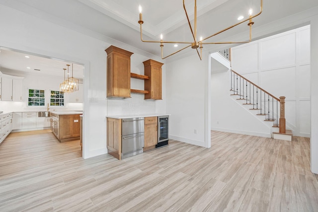 kitchen with wine cooler, light wood-style floors, brown cabinets, a sink, and a notable chandelier