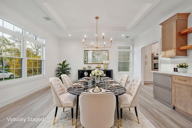dining room featuring an inviting chandelier, a raised ceiling, light wood-style flooring, and visible vents