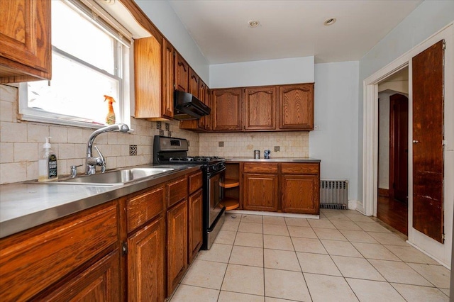 kitchen with exhaust hood, brown cabinetry, tasteful backsplash, a sink, and black gas range oven