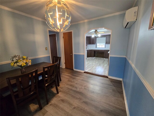 dining area featuring an inviting chandelier, a wall mounted AC, ornamental molding, arched walkways, and wood finished floors