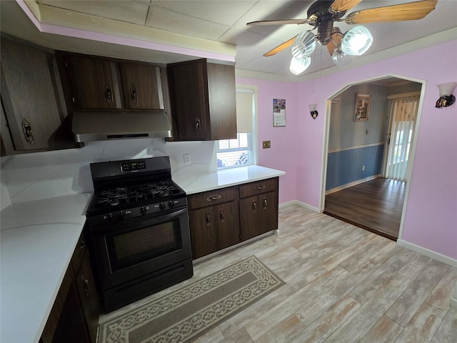 kitchen featuring ceiling fan, light countertops, range hood, and black gas range