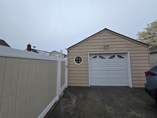 detached garage featuring driveway and fence