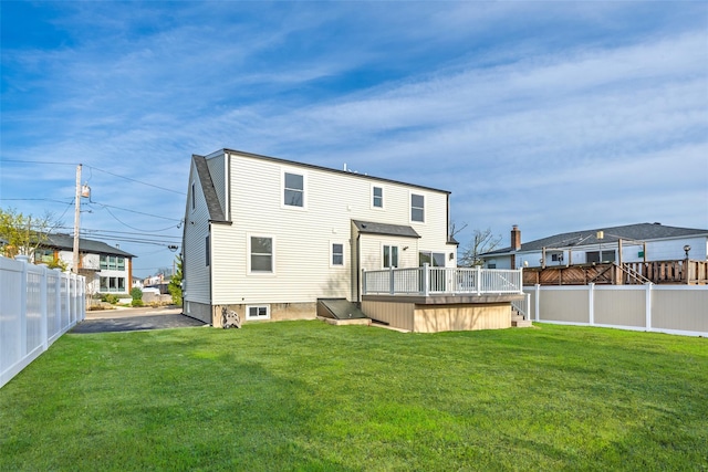 rear view of property with a deck, fence, and a lawn