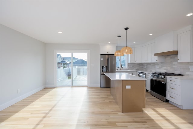 kitchen with a center island, backsplash, appliances with stainless steel finishes, and light wood finished floors