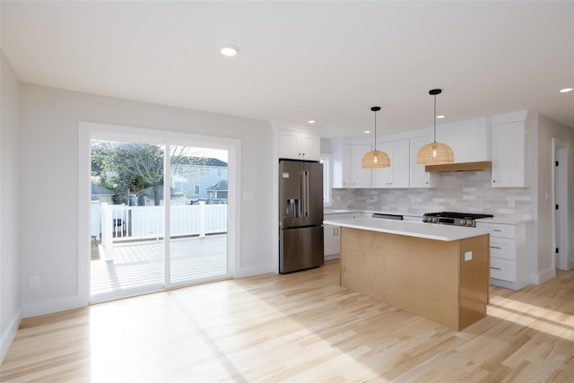 kitchen with light wood-style flooring, light countertops, backsplash, a center island, and stainless steel refrigerator with ice dispenser