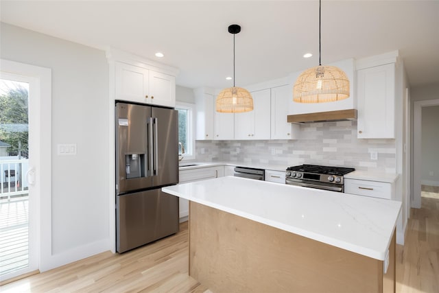 kitchen featuring stainless steel appliances, light countertops, light wood-style flooring, and decorative backsplash
