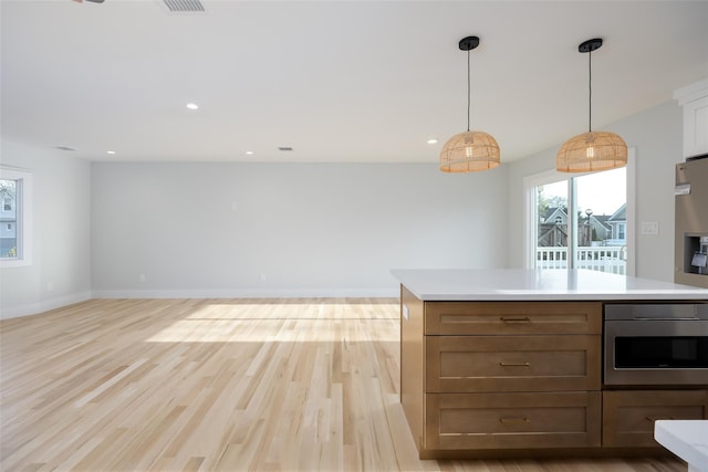kitchen featuring light wood-type flooring, light countertops, recessed lighting, and hanging light fixtures